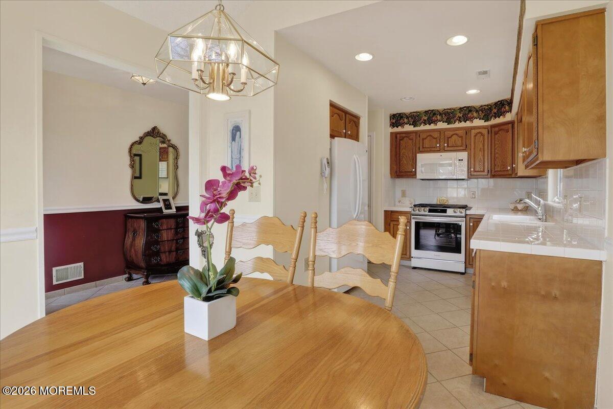 18 Angus Court Jackson, NJ 08527 - Photo 8 of 45 a dining room with wooden floor a chandelier a wooden table and chairs