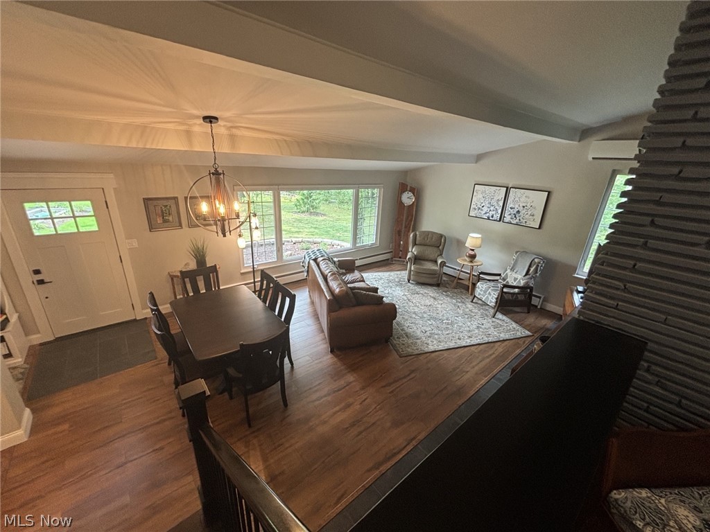 Open-concept main living area with German engineered wood flooring, a contemporary chandelier, a large picture window with custom window treatments, and a fireplace with Regency blower.