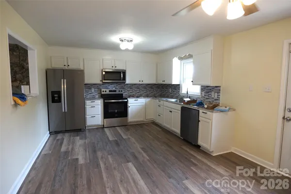 a kitchen with granite countertop a refrigerator stove top oven and sink