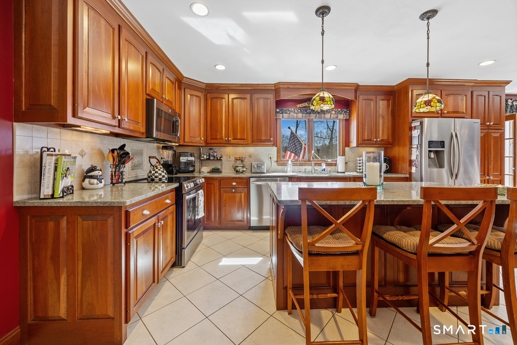 63 Lyman Road Wolcott, CT 06716 - Photo 13 of 70 a kitchen with stainless steel appliances granite countertop a stove top oven a refrigerator and island