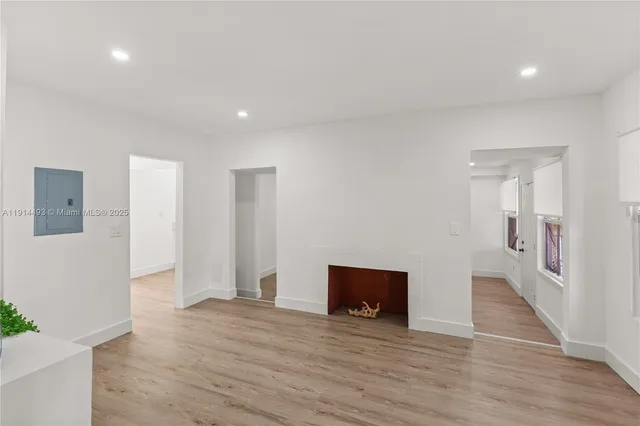 a view of an empty room with wooden floor and a fireplace