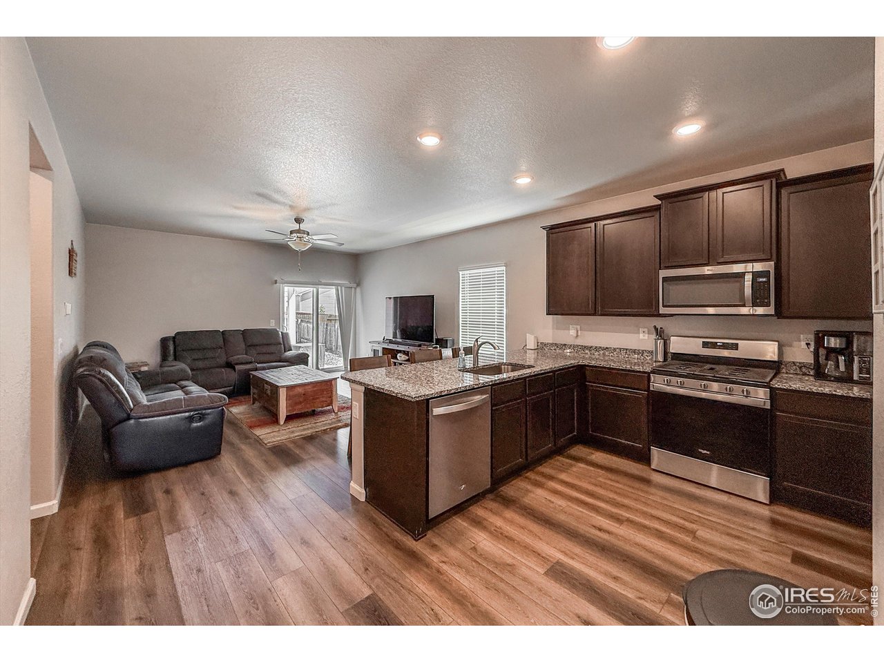 2287 Murray Street Mead, CO 80542 - Photo 8 of 38 a kitchen with stainless steel appliances kitchen island granite countertop a stove top oven a sink dishwasher a dining table and chairs with wooden floor