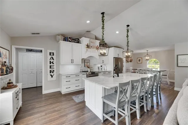 a kitchen with stainless steel appliances a dining table chairs refrigerator sink and cabinets
