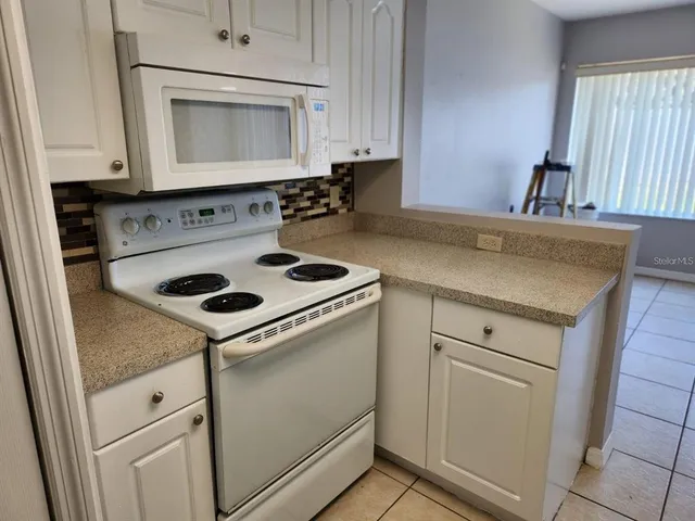 a kitchen with granite countertop white cabinets white stove a sink and dishwasher