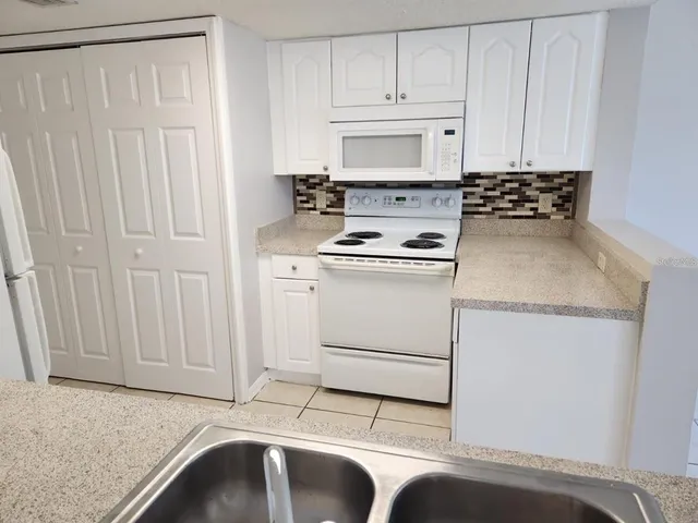 a kitchen with white cabinets and white appliances