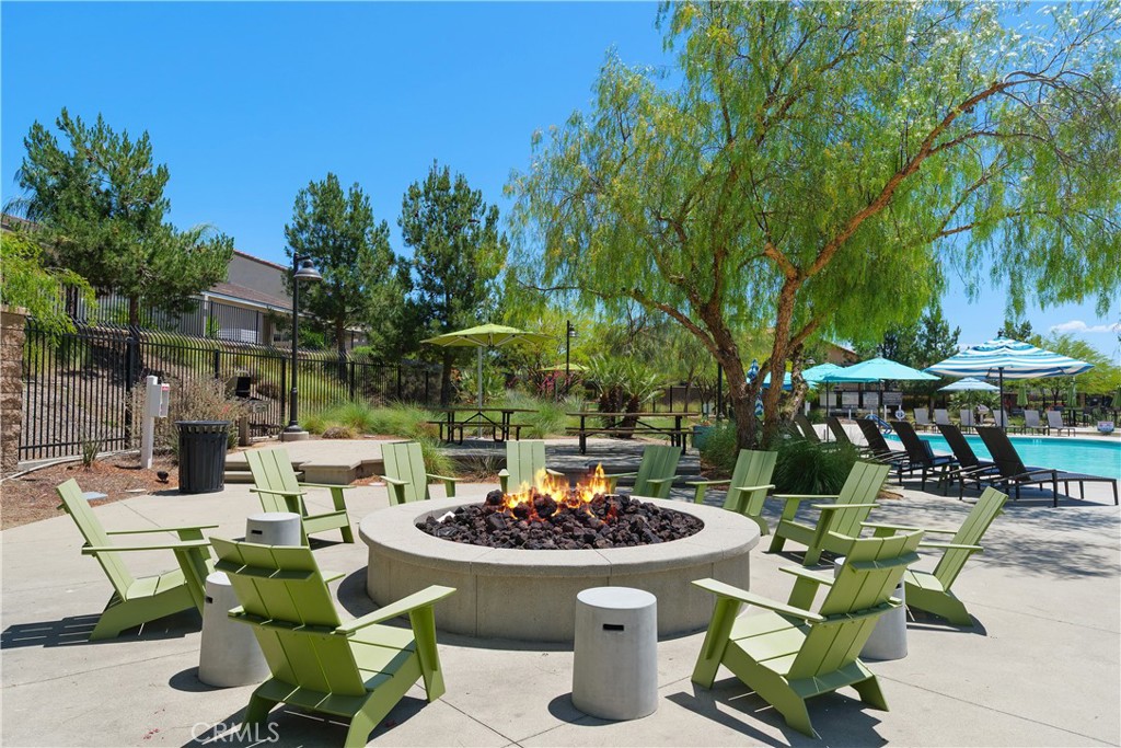 34727 Ribbon Grass Way Murrieta, CA 92563 - Photo 36 of 54 The Oasis firepit offers a relaxing vantage point overlooking the sparkling pool, framed by a beautiful backdrop of mature trees—creating a warm, inviting setting for evening gatherings and sunset views.
