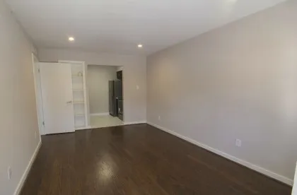a view of an empty room with wooden floor and closet