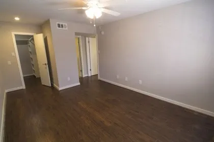 an empty room with wooden floor and chandelier fan