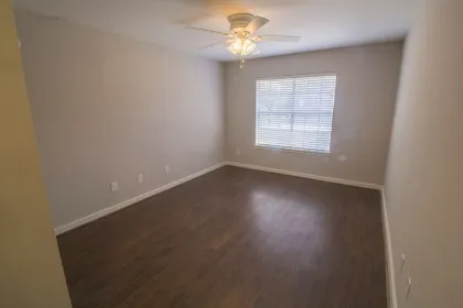 an empty room with a window and a fan