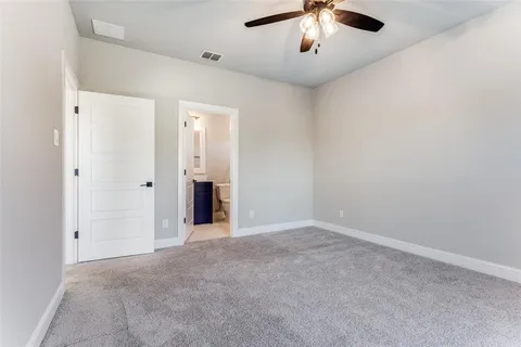 an empty room with chandelier fan and windows