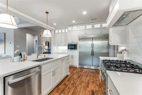 a kitchen with kitchen island a counter space a sink appliances and cabinets