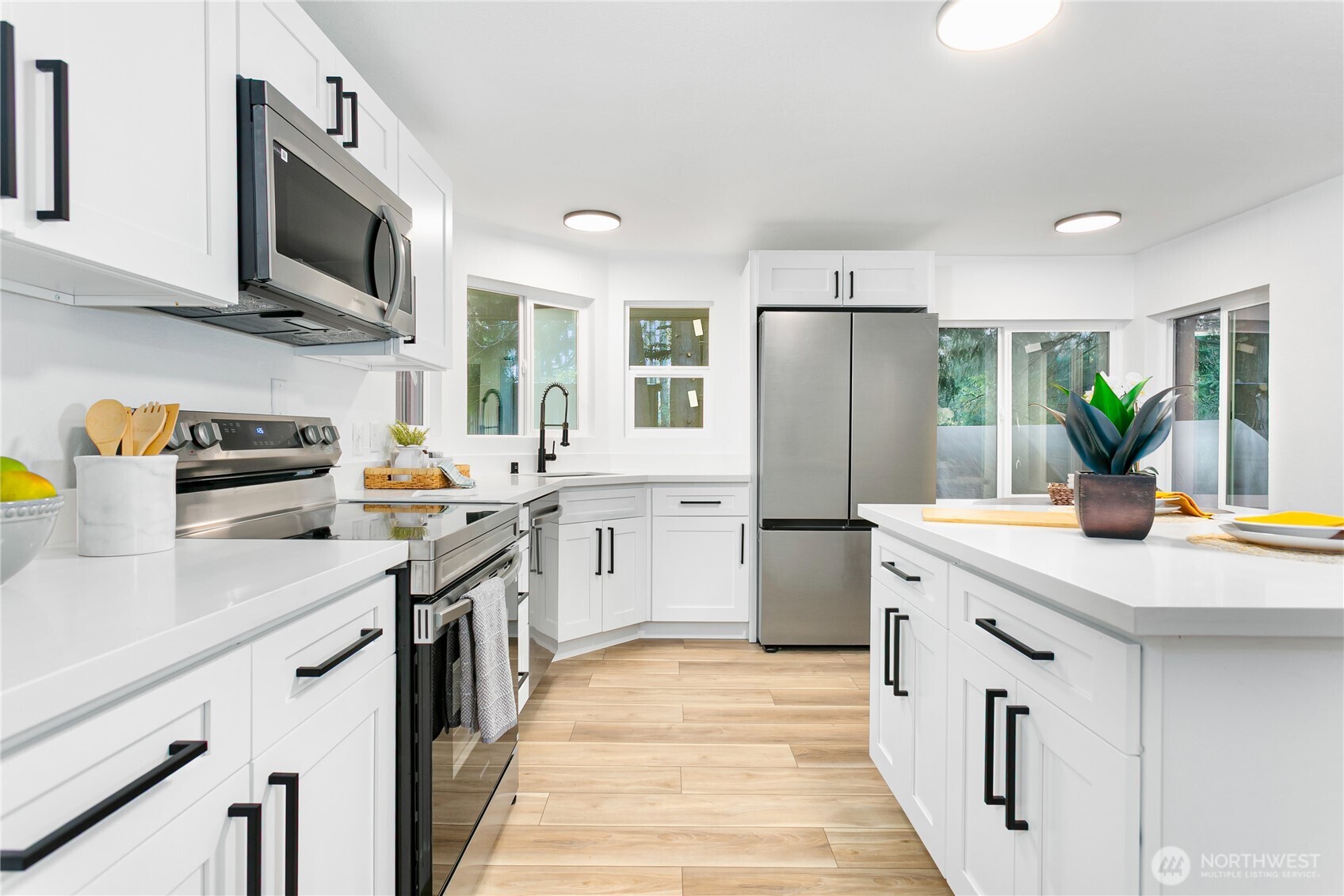 8021 Northeast Eglon Road Kingston, WA 98346 - Photo 8 of 35 a kitchen with stainless steel appliances a sink dishwasher stove refrigerator and microwave with wooden floor
