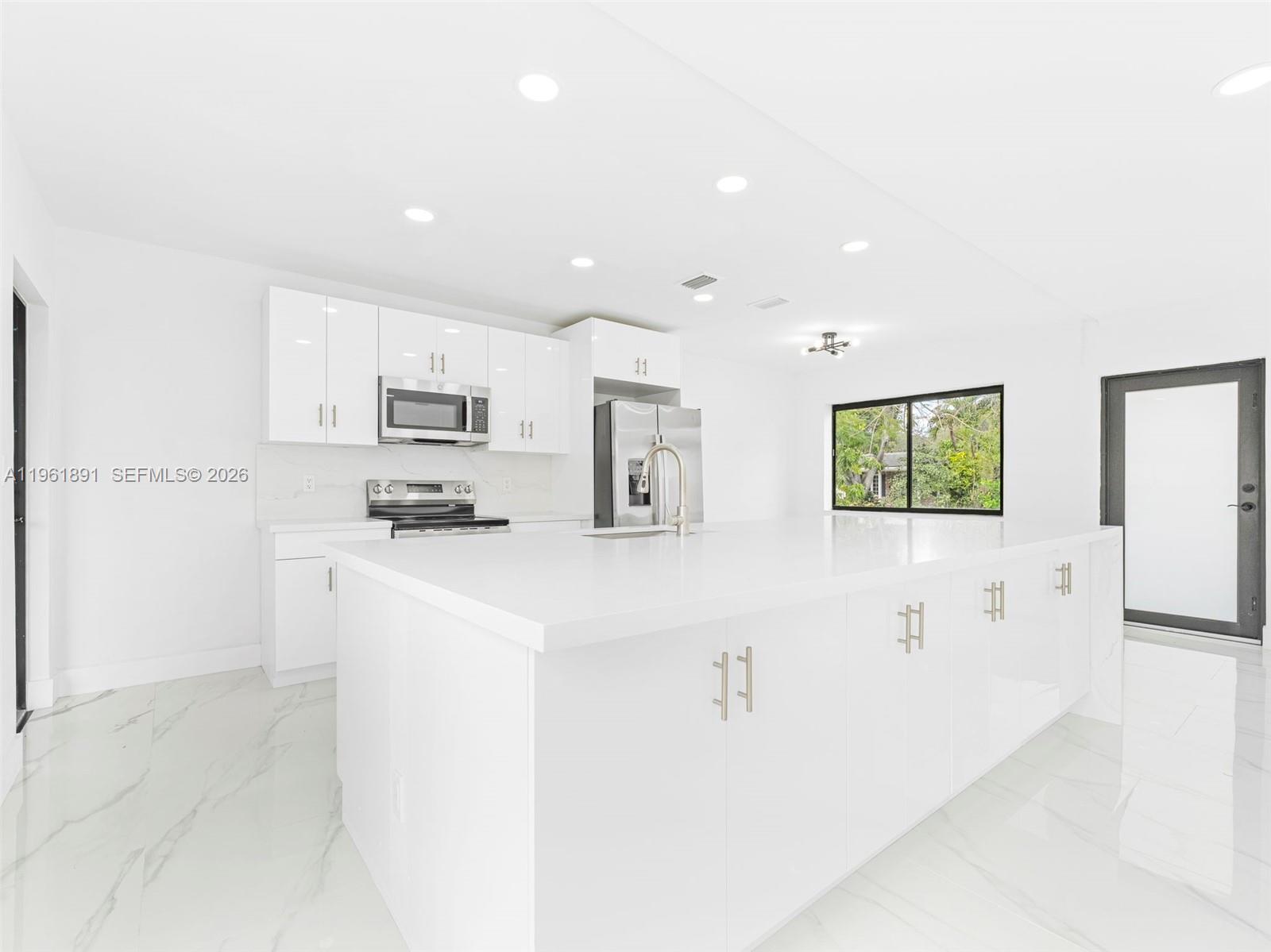 2500 Southwest 23rd Terrace Miami, FL 33145 - Photo 13 of 36 a kitchen with kitchen island a refrigerator sink and white cabinets