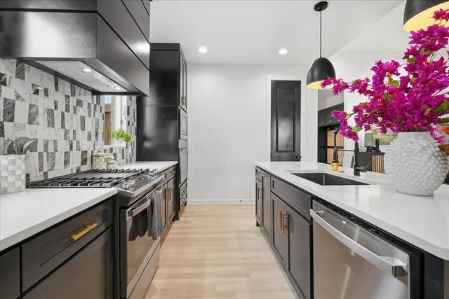 a kitchen with granite countertop a sink flowers stove and cabinets
