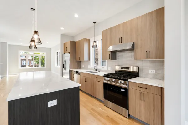 a kitchen with stainless steel appliances granite countertop a stove a sink and a refrigerator