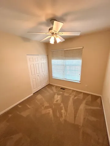 an empty room with a chandelier fan and windows