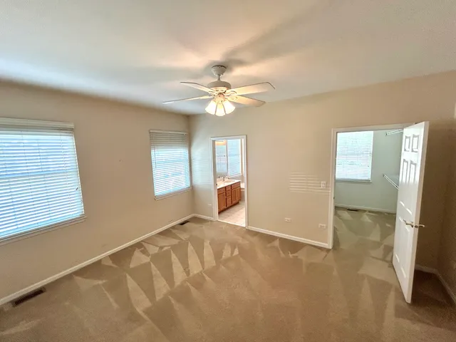 an empty room with windows and fan