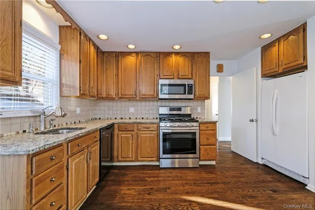a kitchen with stainless steel appliances granite countertop a stove a sink and a microwave