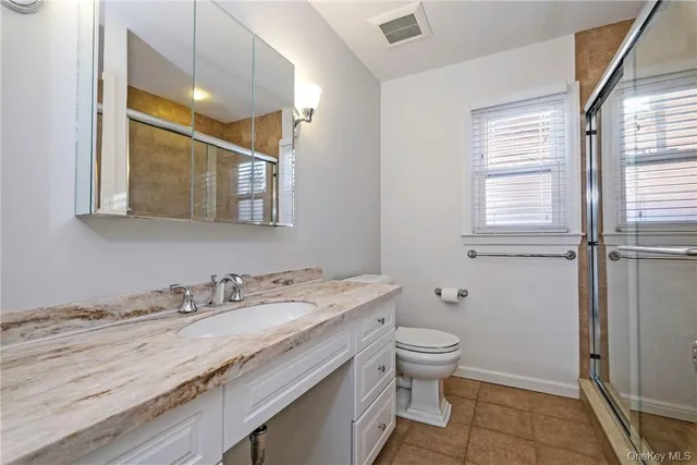 a bathroom with a granite countertop sink a toilet and a mirror
