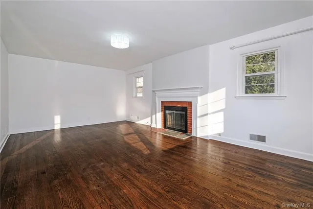 an empty room with wooden floor fireplace and windows