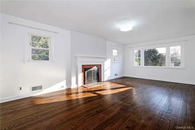 a view of empty room with wooden floor and fireplace