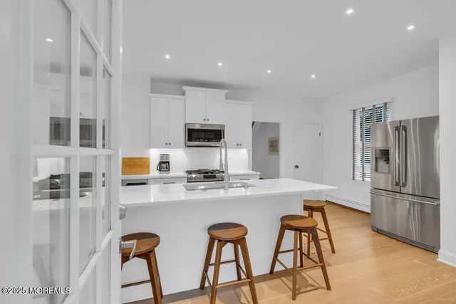 a kitchen with stainless steel appliances a refrigerator a stove a sink cabinets and a dining table