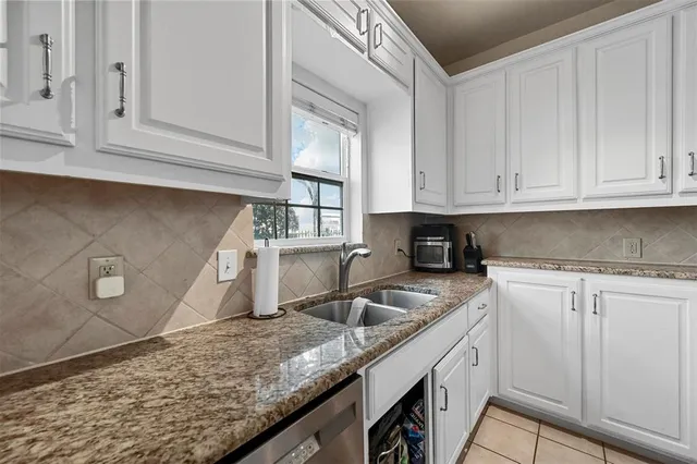 a kitchen with granite countertop white cabinets and a sink