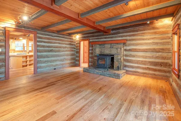 a view of an empty room with wooden floor fireplace and a window