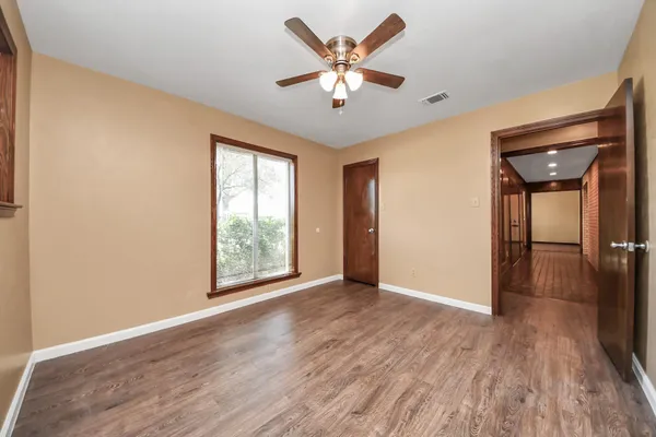 a view of an empty room with window and wooden floor