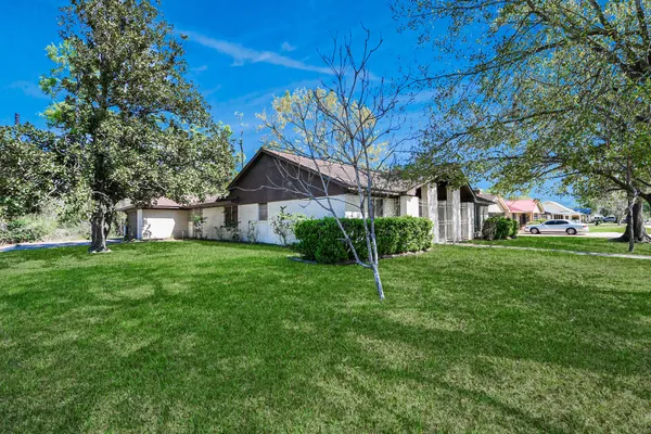 a view of a house next to a big yard and large trees