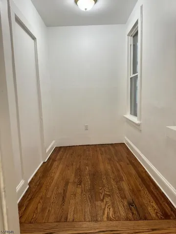 a view of a room with wooden floor and small window