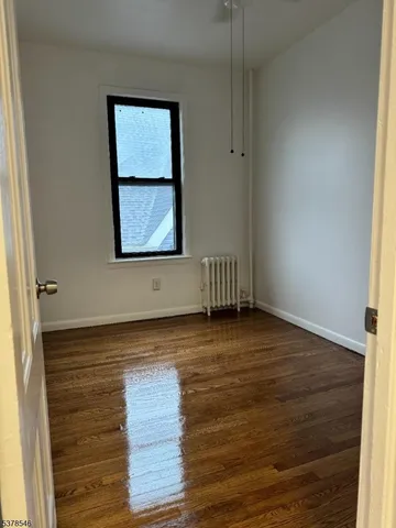 an empty room with wooden floor and window
