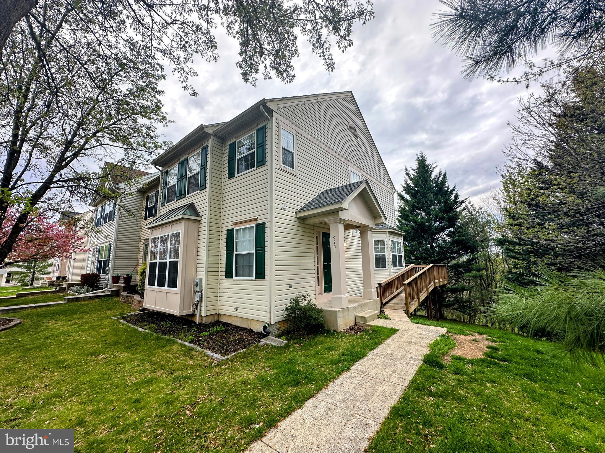 a view of a white house with a big yard plants and large trees