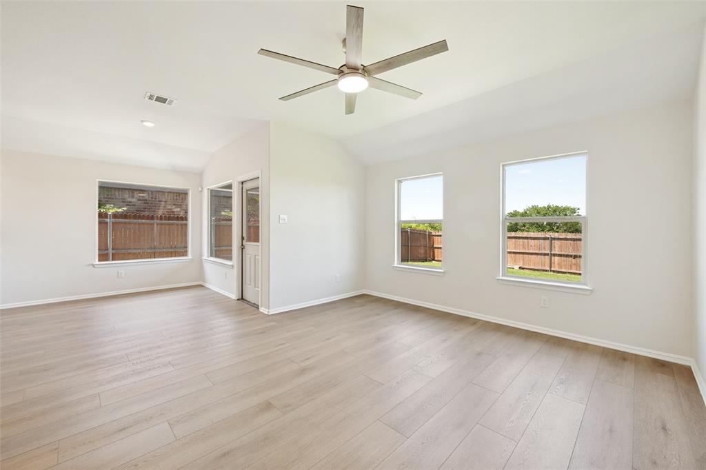 857 Watson Way Crowley, TX 76036 - Photo 12 of 25 Spacious room featuring vaulted ceilings, wood-finish flooring, a modern ceiling fan, and multiple windows providing ambient light