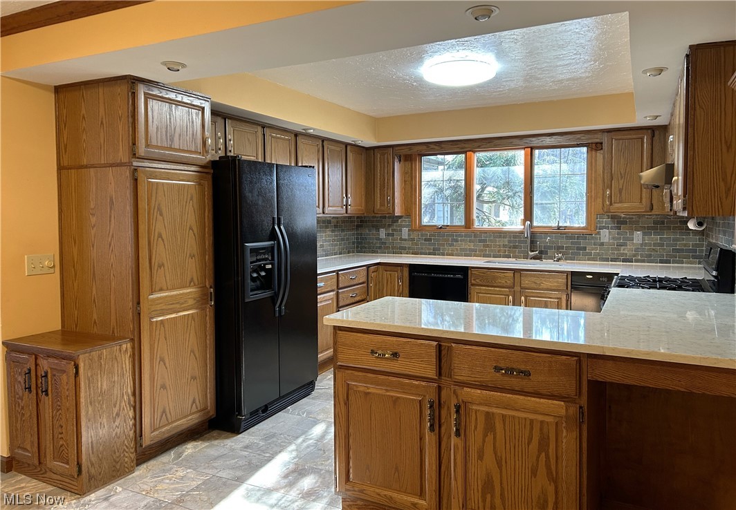 7855 Mulberry Road Chesterland, OH 44026 - Photo 6 of 46 Kitchen featuring Quartz countertops,marble flooring, kitchen peninsula, black appliances, and tile backsplash with a pantry.