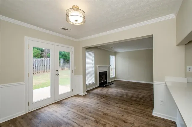 an empty room with wooden floor fireplace and windows
