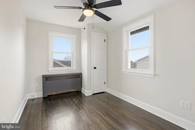 an empty room with wooden floor fan and windows