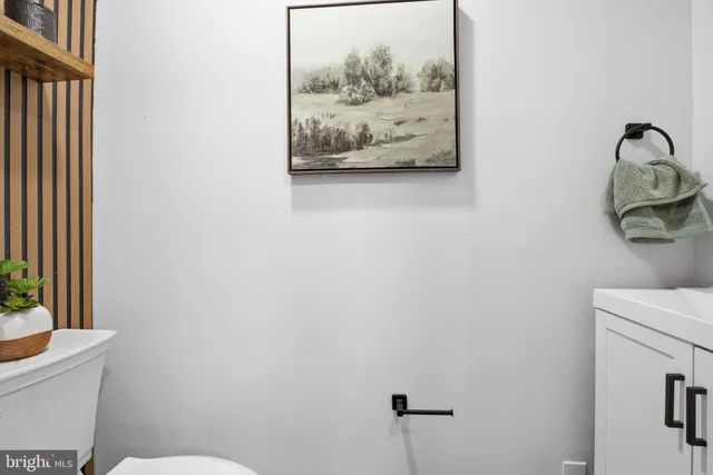 a bathroom with a toilet and a painting on the wall
