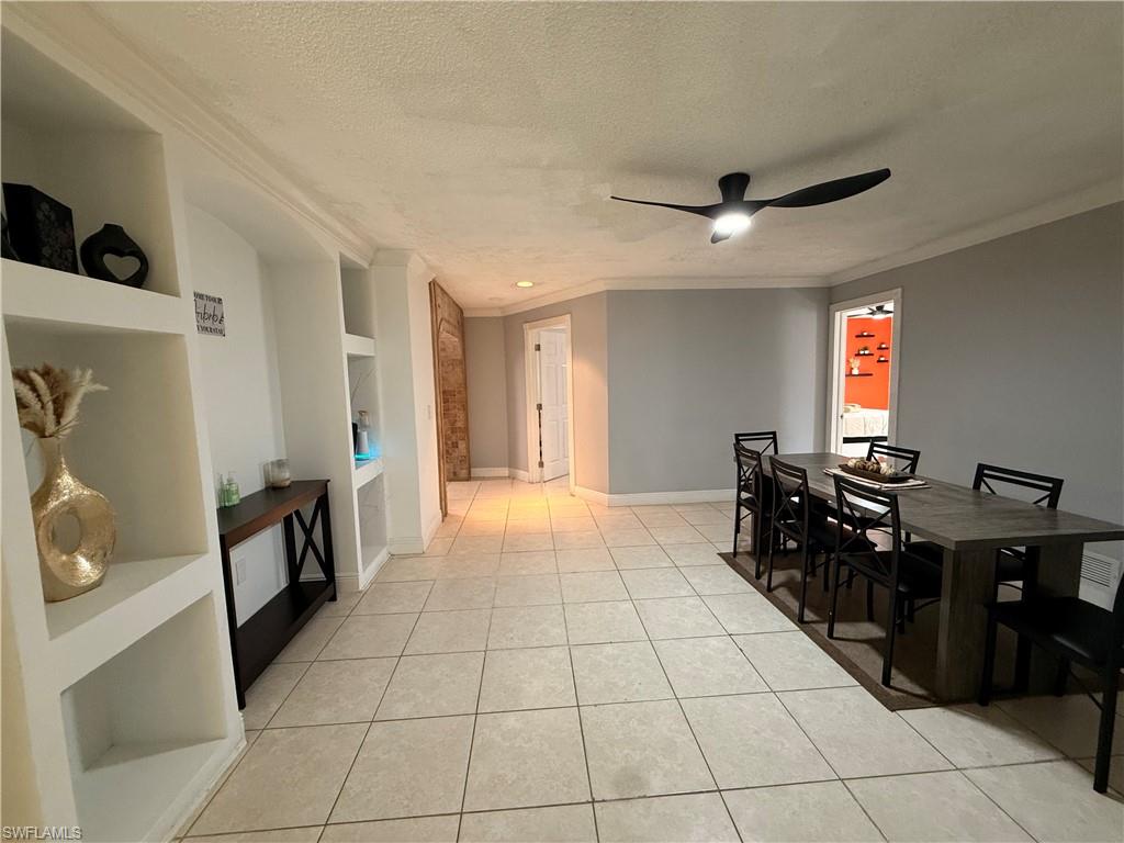 Dining area featuring built in features, a textured ceiling, light tile patterned flooring, ceiling fan, and ornamental molding