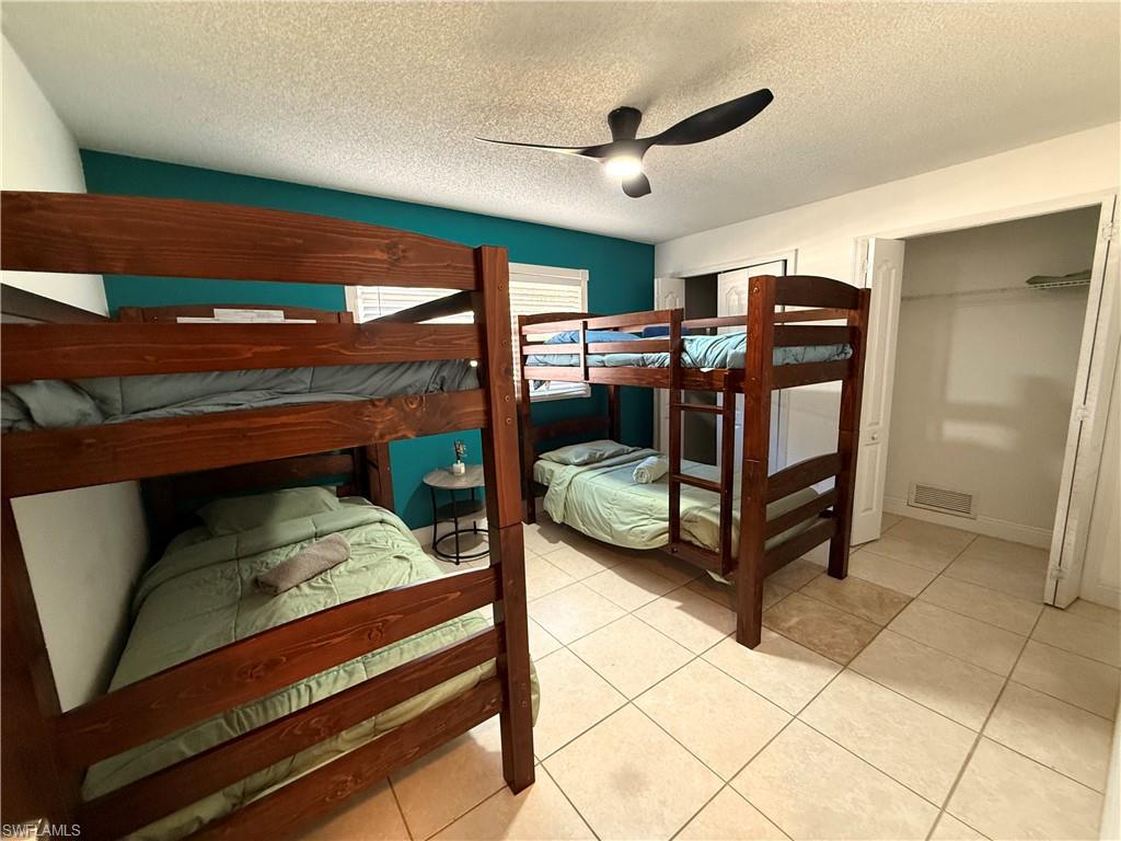 3536 Bolero Way Naples, FL 34105 - Photo 11 of 25 Bedroom with a ceiling fan, a textured ceiling, and light tile patterned flooring