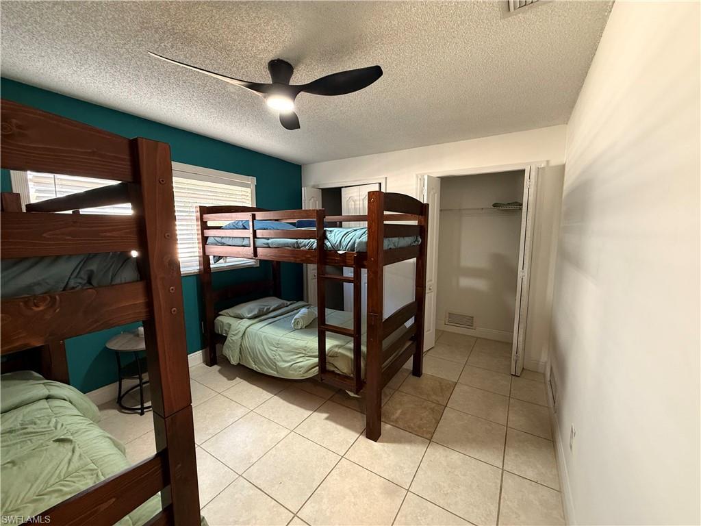 3536 Bolero Way Naples, FL 34105 - Photo 12 of 25 Bedroom featuring a ceiling fan, a textured ceiling, light tile patterned floors, and a closet