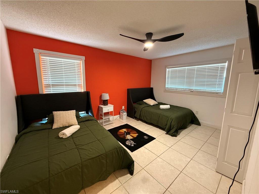 3536 Bolero Way Naples, FL 34105 - Photo 13 of 25 Bedroom with light tile patterned floors, a textured ceiling, multiple windows, and ceiling fan