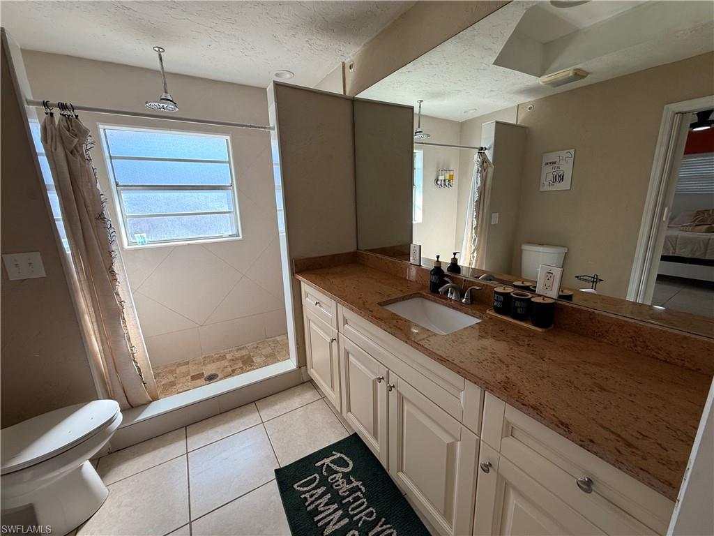 3536 Bolero Way Naples, FL 34105 - Photo 22 of 25 Bathroom with a stall shower, vanity, light tile patterned flooring, a textured ceiling, and ensuite bathroom