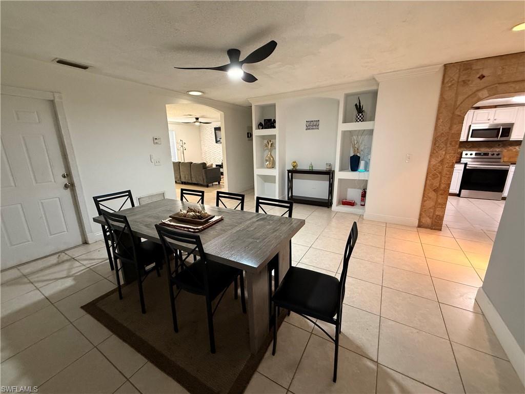 3536 Bolero Way Naples, FL 34105 - Photo 23 of 25 Dining room featuring built in features, arched walkways, light tile patterned floors, a textured ceiling, and ceiling fan