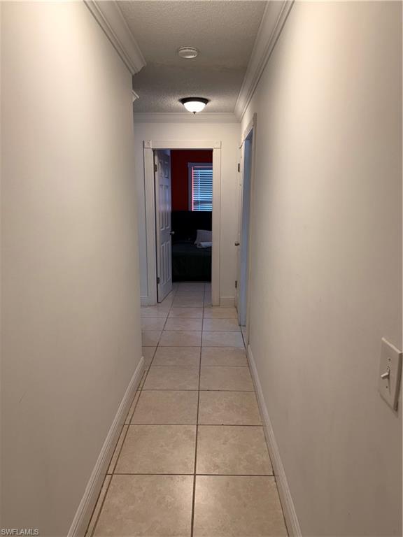 3536 Bolero Way Naples, FL 34105 - Photo 10 of 25 Hall featuring a textured ceiling, light tile patterned floors, and crown molding