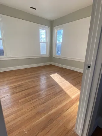 a view of empty room with window and wooden floor