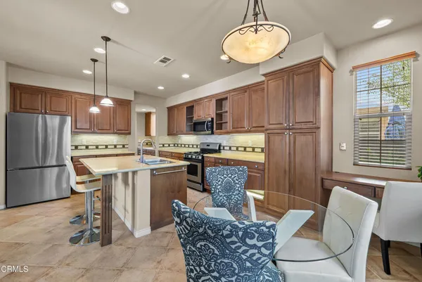 a kitchen with a refrigerator a stove a sink dishwasher with a dining table and chairs