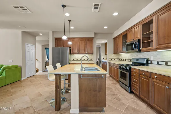 a kitchen that has a sink a stove and chairs