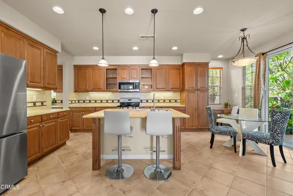 a kitchen with stainless steel appliances kitchen island granite countertop a table chairs and a refrigerator