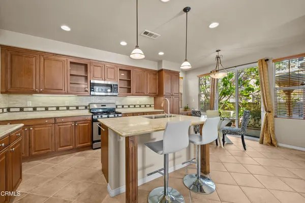 a kitchen with kitchen island granite countertop a stove a sink a oven a dining table and chairs with wooden floor